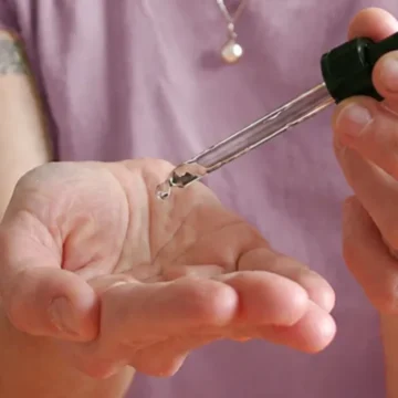 Femme déposant une goutte d'huile essentielle au creux de sa main avec une pipette, geste d'application découvert lors de l'atelier d'aromathérapie énergétique